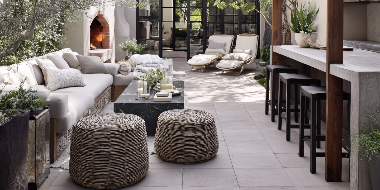 Shaded outdoor lounge with cushioned seating and a stone fireplace
